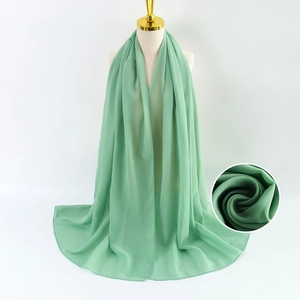 Elegante bufanda de gasa de perlas verde en maniquí con detalle de cerca de la textura de tela