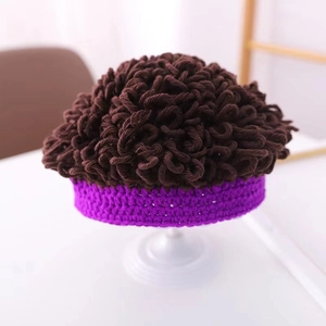 Dettaglio cappello a parrucca per neonati all'uncinetto con ricci marroni e bordo viola