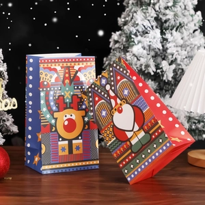 Christmas gift paper bags with Santa and reindeer designs on a festive wood table