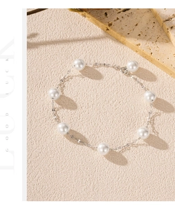 Detailed view of an S925 silver pearl bracelet with eight lustrous white pearls on sand