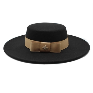 Detail of black wool fedora featuring khaki ribbon bow and antique metal bee charm