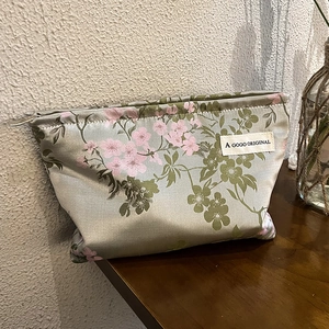 Detail of silk satin makeup bag featuring elegant cherry blossom print and secure zipper