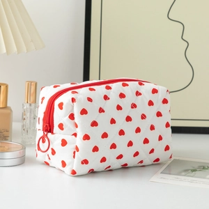 Close-up of quilted cotton makeup bag with red heart pattern and circular ring zipper