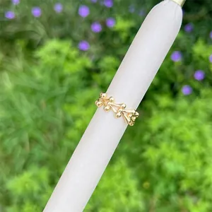 18K gold plated bone-shaped link ring displayed on a stand with nature background
