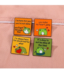 Set of four cute enamel frog badges with heart-warming English phrases on pink fabric