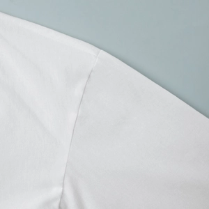 Detailed close-up of high-quality white cotton stitching and shoulder seam construction