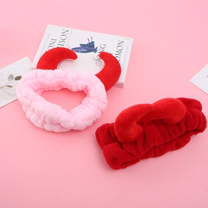 Détail de bandeaux cornes de diable en peluche rose et rouge sur fond rose