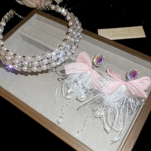 Detail of luxury pearl headband and pink bow feather earrings in a jewelry box