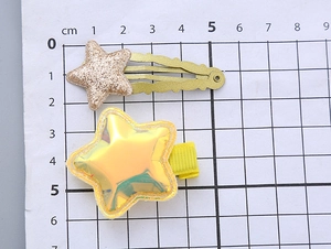 Detailed size measurement of glitter star hair clips with centimeter ruler on grid paper