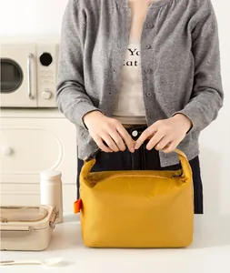 Close-up of yellow insulated lunch bag with black buckle handle in a home kitchen setting