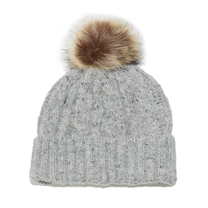 Detail of grey cable knit winter beanie featuring a large fluffy faux fur pom-pom topper