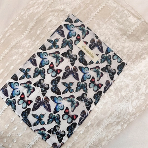 Gros plan sur tissu blanc à motifs papillons bleus et étiquette tissée de marque Sozakka