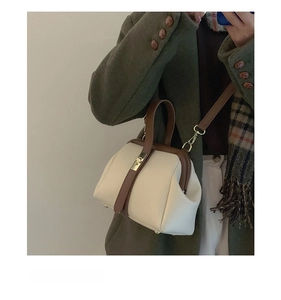 Retro contrast color handbag with metal clasp shown in a stylish lifestyle setting