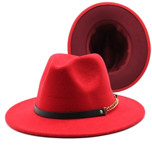 Detail of red wool fedora featuring black leather band and gold chain accent decoration