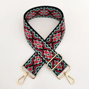 Close-up of ethnic jacquard embroidery pattern and gold metal buckles on bag strap