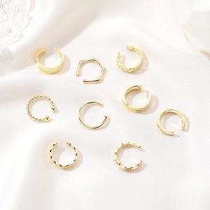 9-piece gold C-shape ear cuff set with twisted and smooth metal textures on white silk