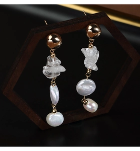 Detailed close-up of Baroque pearl earrings with crystal on a vintage wooden stand