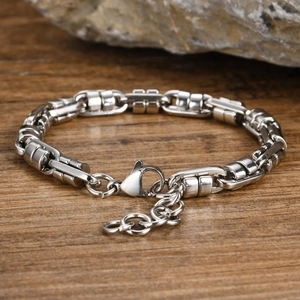 Macro detail of men's stainless steel chain bracelet with lobster clasp on a rock