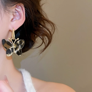 Detail of leopard print butterfly earring worn by a model in a vintage aesthetic