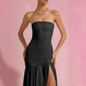 Detail of black strapless evening gown with sparkling sequins and high slit skirt