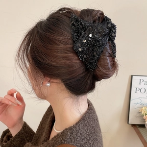 Macro detail of acrylic triangle shark clip with rhinestones worn on elegant hair updo