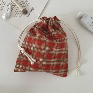 Macro shot of red and green plaid drawstring pouch with cotton cords for storage