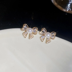 Macro shot of silver needle bow earrings with white pearl and sparkling baguette zircons