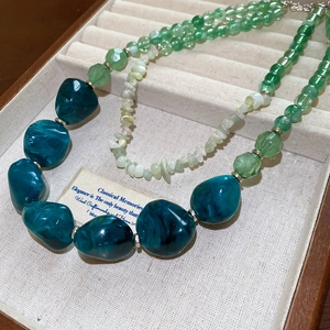 Detailed shot of dark green marbled beads and multifaceted stones on an acrylic necklace
