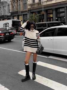 Detail view of oversized black and white striped knit sweater and black leather handbag
