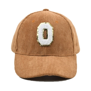 Detail der braunen Cord-Baseballkappe mit flauschigem O-Patch und goldenen Pailletten
