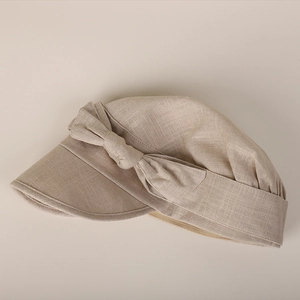 Detailed side view of beige cotton linen newsboy cap with bow tie decoration
