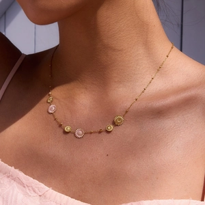 Gold plated stainless steel necklace featuring pink daisy flower charms on a model