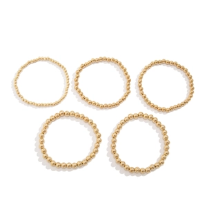 Set of 5 golden beaded bracelets with heart pendant charm on a white background