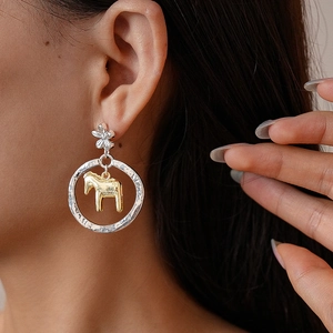 Orecchini a fiori cavi in argento con pendente a forma di pony dorato su una modella
