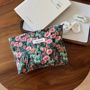 Close-up of small floral fabric pouch with simple wish label on rustic wooden table