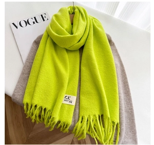 Detailed view of neon green tassel scarf with soft texture and chic brand label detail