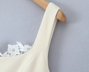 Makroaufnahme der cremefarbenen Spitze und des eckigen Ausschnitts am Kleid