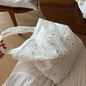 Detailed view of white cotton tote bag featuring intricate floral eyelet embroidery