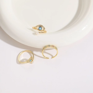 Three-piece gold plated evil eye rings set with blue enamel and pearls on ceramic plate