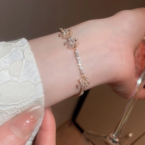 Close-up of elegant gold flower bracelet with zircon inlay worn on a female wrist