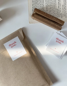 Detail showing white Thank You cards with red heart and brown kraft envelopes
