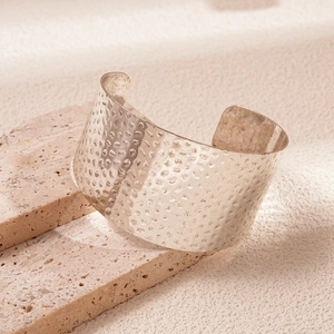 Macro shot of silver wide hammered texture cuff bracelet on minimalist stone base
