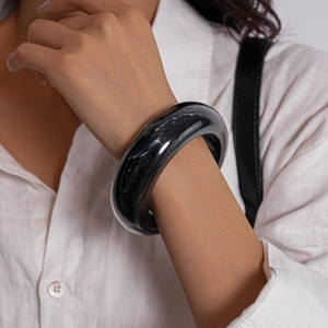 Detail of chunky black resin bangle with marble texture on a woman's wrist