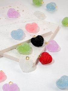 Macro detail of sugar-textured resin heart pendants with gold rings in various colors