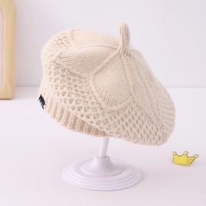 Detail of cream knit beret showing textured diamond pattern and top stalk detail