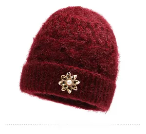 Close-up of fluffy dark red knitted hat with a gold floral pearl brooch detail