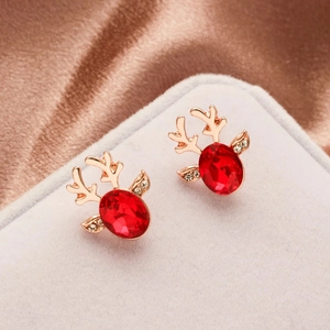 Detailed shot of Christmas reindeer stud earrings with red crystal on silk background