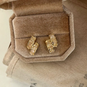 Gros plan de boucles d'oreilles plaquées or 14k avec des éclats de verre étincelants.