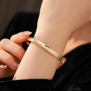 Detailed view of golden open bangle featuring a fine hexagonal honeycomb texture