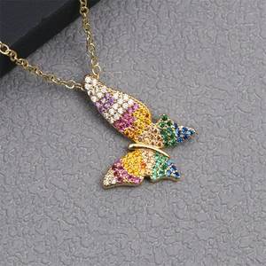 Close-up of gold butterfly pendant with colorful zircon stones on a grey textured background